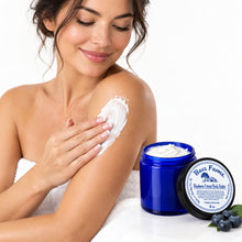 Load image into Gallery viewer, An open cobalt blue jar of Bass Farms Blueberry Extract Body Butter with white cream visible inside, shown alongside its black lid on a plain white background.