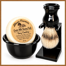 Load image into Gallery viewer, A shaving set including a black shaving bowl, a goat milk soap shaving puck, a brush, and a stand, with the brand 'Bass Farms' visible on the packaging.
