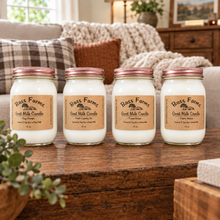 Load image into Gallery viewer, Four glass mason jar candles with cream-colored wax and tan labels, arranged in a row against a solid black background. The labels read 'Bass Farms Good Milk Candle'.