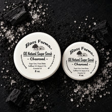Load image into Gallery viewer, Two containers of Bass Farms All Natural Sugar Scrub with one labeled as charcoal. The containers are placed on a wooden surface.