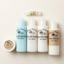 Load image into Gallery viewer, Travel size personal care products from Bass Farms including body lotion, shampoo and conditioner, body wash, triple B hydrating cream, and lip balm, arranged on a wooden surface.
