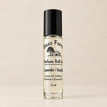 Load image into Gallery viewer, A clear glass bottle with a black plastic cap labeled as 'Perfume Roll', placed on a wooden surface with green leaves in the background.