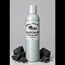 Load image into Gallery viewer, A bottle of Bass Farms Goat Milk Body Wash with Charcoal, with a white label and charcoal-colored liquid inside, placed on a surface with a tiled background.