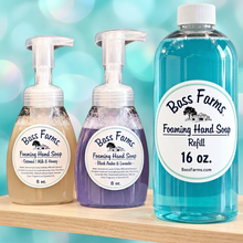 Load image into Gallery viewer, Three Bass Farms Foaming Hand Soap products displayed on a rustic wooden shelf against a dark wood background: a 16 oz. refill bottle filled with bright blue liquid, an 8 oz.

